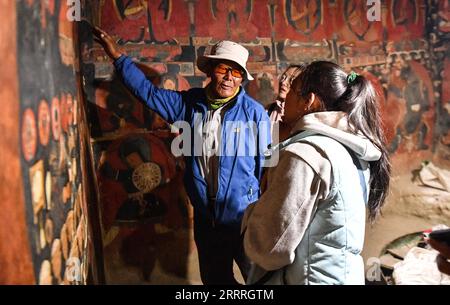 230528 -- ZANDA, 28. Mai 2023 -- Rigzin Wangzhab stellt in einer Grotte im Kreis Zanda der Präfektur Ngari, der autonomen Region Tibet im Südwesten Chinas, am 26. Mai 2023 Wandbilder für Touristen vor. Versteckt zwischen Sandsteinhügeln im abgelegenen Westen Tibets, ist ein Abschnitt von Wabenhöhlen weit über die Reichweite der meisten Reisenden hinaus. Die 1.000 Jahre alten Höhlen in der Präfektur Ngari der Autonomen Region Tibet, bekannt als Donggar- und Piyang-Grotten, beherbergen eine der weltweit größten Sammlungen tibetischer buddhistischer Wandbilder. Rigzin Wangzhab, 75, bewacht das Gelände seit über 20 Jahren. Als ich sehr alt war Stockfoto