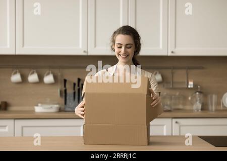 Glückliche schöne junge Kundenfrau, die das Paket öffnet Stockfoto