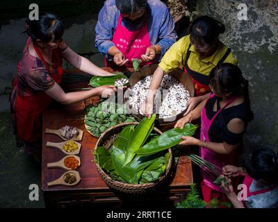 230621 -- NINGGUO, 21. Juni 2023 -- die Dorfbewohner machen Zongzi, einen pyramidenförmigen klebrigen Reisknödel, der in Bambus- oder Schilfblätter gehüllt ist, während das Dragon Boat Festival in Hule, Stadt Ningguo, Ostchinesische Provinz Anhui, 17. Juni 2023 naht. Hule Town, eine antike Stadt in der ostchinesischen Provinz Anhui, hat eine Tradition in der Laternen-Aufführung, um Feste zu feiern. Während sich das Dragon Boat Festival nähert, tanzen die Dorfbewohner mit Laternen in Form von Fischen und Drachen und legen lotusförmige Wasserlaternen in den Fluss. Eine Reihe von Aktivitäten, darunter das Bankett am langen Tisch und Stockfoto