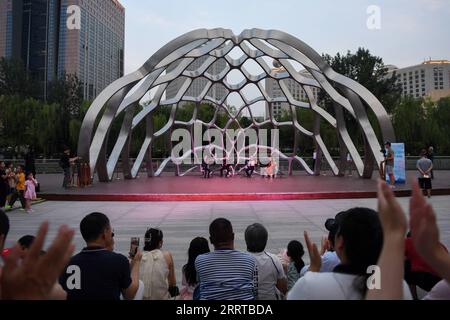 230713 -- PEKING, 13. Juli 2023 -- Menschen beobachten eine Abendvorstellung am Liangma Fluss in Peking, Hauptstadt von China, 23. Juni 2023. Die seine, der zweitgrößte Fluss Frankreichs, schlängelt sich durch das Herz von Paris. Sie fließt von West nach Ost und teilt die Stadt in das ikonische linke und rechte Ufer. Das linke Ufer ist geprägt von einem künstlerischen Ambiente, das mit Cafés, Theatern und Buchläden geschmückt ist und einen Hafen für den literarischen Kreis und ein Kulturparadies schafft. Auf der anderen Seite beherbergt das rechte Ufer prestigeträchtige Sehenswürdigkeiten wie den Louvre, den ehemaligen königlichen Palast und die Elys Stockfoto