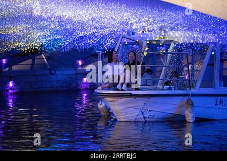 230713 -- PEKING, 13. Juli 2023 -- Ein Touristenboot passiert die Haoyun Good Luck Bridge über den Liangma Fluss in Peking, Hauptstadt von China, 16. Juni 2023. Die seine, der zweitgrößte Fluss Frankreichs, schlängelt sich durch das Herz von Paris. Sie fließt von West nach Ost und teilt die Stadt in das ikonische linke und rechte Ufer. Das linke Ufer ist geprägt von einem künstlerischen Ambiente, das mit Cafés, Theatern und Buchläden geschmückt ist und einen Hafen für den literarischen Kreis und ein Kulturparadies schafft. Auf der anderen Seite beherbergt das rechte Ufer prestigeträchtige Sehenswürdigkeiten wie den Louvre, das ehemalige königliche Viertel Stockfoto