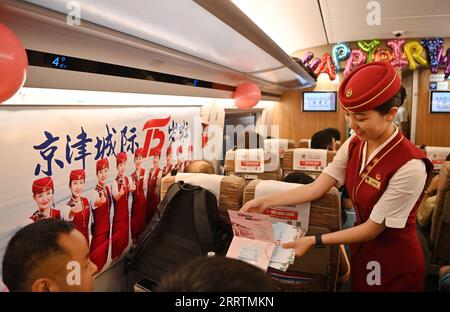 230801 -- TIANJIN, 1. Aug. 2023 -- Ein Dirigent präsentiert einem Passagier ein 15-jähriges Souvenir an Bord eines Zuges, der auf der Intercity-Bahn Peking-Tianjin verkehrt, 1. Aug. 2023. Die Intercity-Bahn Peking-Tianjin feierte ihren 15. Jahrestag der Eröffnung am Dienstag. Als erste Hochgeschwindigkeitsbahn HSR mit einer planmäßigen Geschwindigkeit von 350 km/h in China beförderte die Intercity-Bahn Peking-Tianjin seit ihrer Inbetriebnahme insgesamt 340 Millionen Passagiere. Bis 2022 verfügte China über 42.000 km Betriebsstrecke (HSR), womit es weltweit den ersten Platz belegte, und die Länge der Hochgeschwindigkeitsstrecke, die regelmäßig mit 350 fuhr Stockfoto