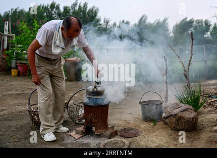 230803 -- TONGLIAO, 3. Aug. 2023 -- Bai Shun kocht Wasser in seinem Haus in Bulteger Gacha, Horqin linkes Flügel hinteres Banner der Stadt Tongliao, Nordchina Innere Mongolei Autonome Region, 2. Aug. 2023. Bulteger Gacha, ein kleines Dorf in Horqin im linken Flügel hinter dem Banner der Stadt Tongliao, befand sich im Zentrum des Horqin Sandy Landes und litt früher unter Wüstenbildung. Seit 2002 hat Bai Shun, ein ortsansässiger mongolischer Bauer, seine Familie dazu gebracht, sich in diesem Dorf zu verwurzeln und sich der Kontrolle der Wüstenbildung zu widmen. Die Überlebensrate der gepflanzten Bäume war zu Beginn aufgrund fehlender Erfahrung niedrig Stockfoto