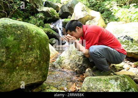 230814 -- LU AN, 14. August 2023 -- Wang Kedong erfrischt sich mit Flusswasser während der Patrouille AN der Tiantangzhai Management Station im Anhui Tianma National Nature Reserve, ostchinesische Provinz Anhui, 12. August 2023. Wang Kedong und Gao Kaiyu, beide 58 Jahre alt, sind Ranger der Tiantangzhai Management Station des Anhui Tianma National Nature Reserve. Sie leben das ganze Jahr über in den Bergen und patrouillieren seit 25 Jahren täglich auf einer Strecke von mehr als 20 Kilometern. Das Anhui Tianma National Nature Reserve wurde 1998 auf der Grundlage von zwei ehemaligen Anhui Provincial Nature Reserves gegründet. I Stockfoto