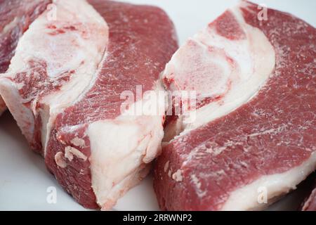 Frische rohe Rindersteaks mit Knochen auf dem Schneidebrett, bereit zum Kochen von Asado Stockfoto