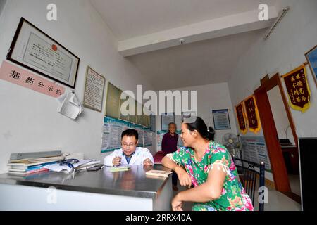 230819 -- NANCHANG, 19. August 2023 -- Xiao Jiulin L spricht mit einem Patienten in seiner Klinik im Dorf Yangang im Kreis Yudu, ostchinesische Provinz Jiangxi, 15. August 2023. ZUM MITNEHMEN: Körperbehinderter Arzt bietet Grundversorgung für Hunderte CHINA-JIANGXI-KÖRPERBEHINDERTER ARZT CN HuxChenhuan PUBLICATIONxNOTxINxCHN Stockfoto