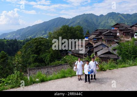 230819 -- QIANDONGNAN, 19. August 2023 -- Wu Changxi C, Wu Tao R und Xiang Changhui posieren für Fotos am Eingang des Dorfes Dingnong im Kreis Rongjiang, Qiandongnan Miao und der autonomen Präfektur Dong, Provinz Guizhou im Südwesten Chinas, 16. August 2023. Wu Changxi, sein Sohn Wu Tao und seine Schwiegertochter Xiang Changhui sind allesamt Landärzte, die in drei Dörfern arbeiten und sich um die Gesundheit von mehr als 820 Haushalten und 3.660 Menschen kümmern. CHINA-GUIZHOU-RURAL DOCTORS-FAMILY CN LIUXXU PUBLICATIONXNOTXINXCHN Stockfoto