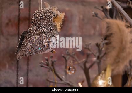 Ein funkelndes künstliches Vogel-Weihnachtsbaumschmuck, aufgenommen durch Tiefenfoto. Der künstliche Vogel ist als Hintergrund gegen die Wand isoliert. Stockfoto
