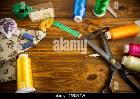 Ein Satz Werkzeuge und Fäden zum Nähen von Kleidung auf Holzhintergrund. Stockfoto