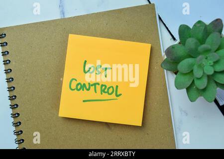 Das Konzept der Lost Control schreibt auf Haftnotizen, die auf einem Holztisch isoliert sind. Stockfoto