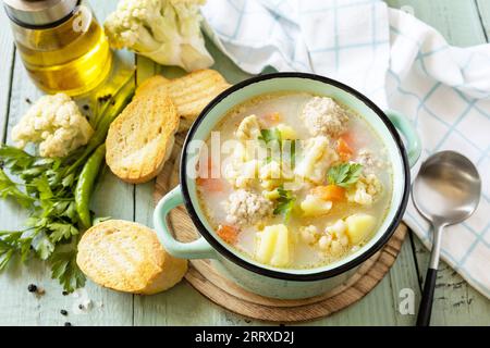 Kohlenhydratarme gesunde Ernährung. Blumenkohlsuppe mit Hähnchenfleischbällchen und Gemüse auf einem rustikalen Holztisch. Stockfoto