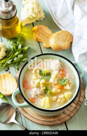 Blumenkohlsuppe mit Hähnchenfleischbällchen und Gemüse auf einem rustikalen Holztisch. Kohlenhydratarme gesunde Ernährung. Stockfoto