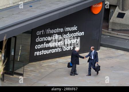 Zwei Geschäftsleute in formellen Anzügen teilen sich am Freitag, den 24. August 2012, einen Handschlag vor dem Haupteingang des Barbican Centre in der City of London. Vor dem Hintergrund der ikonischen Brutalistik-Architektur des EC2-Anwesens hält die Szene ein professionelles Treffen während des geschäftigen Sommers der Olympischen Spiele 2012 in London fest. Zu dieser Zeit war das Barbican ein wichtiger kultureller Drehpunkt für das „London 2012 Festival“ und veranstaltete Weltklasse-Ausstellungen und -Aufführungen für ein internationales Publikum Stockfoto