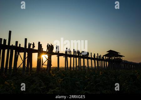 Silhouette der U bein-Brücke bei Sonnenuntergang mit Sonnenstrahlen unter der Brücke in Amarapura, Mandalay, Myanmar Stockfoto