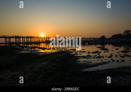Silhouette der U-Bein-Brücke mit Reflexion im Wasser bei Sonnenuntergang in Amarapura, Mandalay, Myanmar Stockfoto