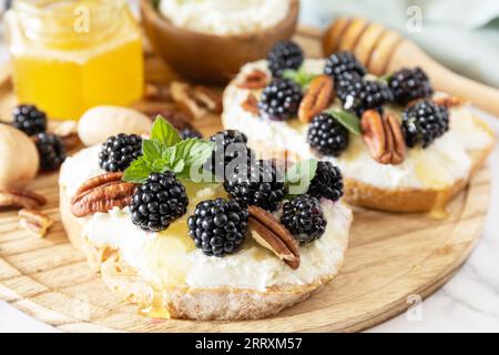 Gesunde Frühstückstoasts. Keto-Diät-Sandwiches. Keto Snack. Süße Bruschetta mit Käse und Beeren, brombeerricotta und Honig auf Marmortisch. Stockfoto