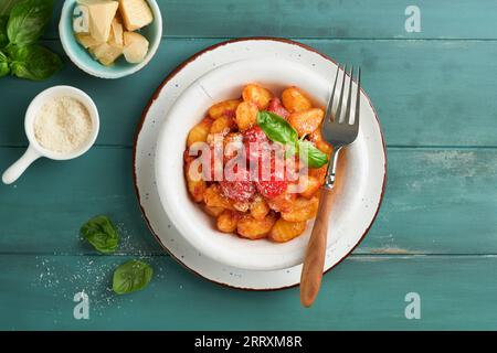 Kartoffelgnocchi. Traditionelle hausgemachte Kartoffelgnocchi mit Tomatensoße, Basilikum und Parmesan auf türkisfarbenem rustikalem Küchentisch. Traditi Stockfoto