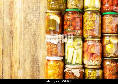 Verschiedene Arten von Gemüse in Dosen in Gläsern auf einem rustikalen Tisch. Gesundes, hausgemachtes fermentiertes Essen. Hauswirtschaft, Herbsternteerhaltung. Anzeigen Stockfoto