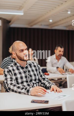 Junger gutaussehender Geschäftsmann, der ein Formular in der Seminarsitzung ausfüllt Stockfoto