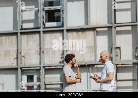 Eine Gruppe von Architekten, die einen modernen Bauplan im Freien analysieren, diskutieren und an der Planung mitarbeiten. Teamarbeit und städtisches Know-how im Bereich Displacement Stockfoto