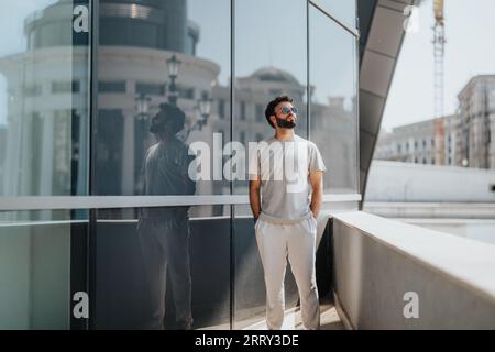 Geschäftsmann, der neben einem großen Business Center steht und über sein nächstes Projekt oder seine nächste Investition nachdenkt. Stockfoto