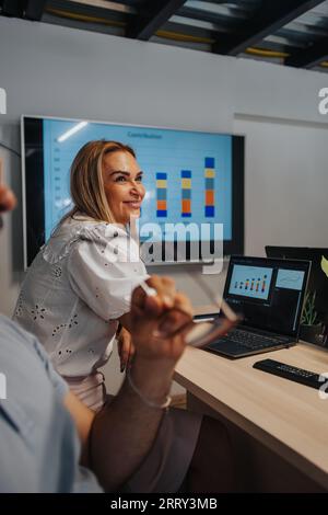 In einem modernen Konferenzraum entwickeln Geschäftspartner Ideen, treffen Entscheidungen und diskutieren über Finanzen. Sie sind vielfältig und engagiert und stehen beispielhaft für eine erfolgreiche t Stockfoto