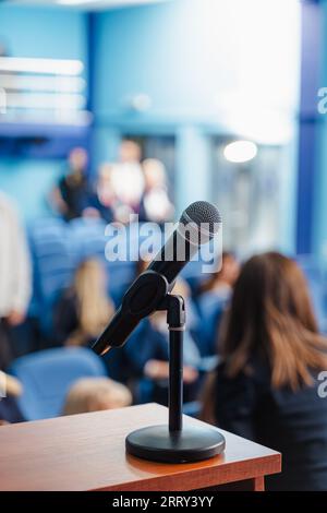 Verschwommener Hintergrund von Studenten, Professoren oder Geschäftsleuten, die auf eine Rede im Konferenzsaal warten. Konzentrieren Sie sich auf das Mikrofon. Stockfoto