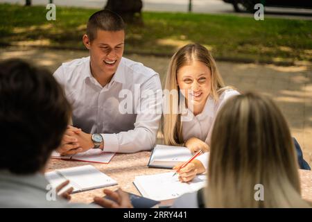 Eine Gruppe von Universitätsstudenten versammelte sich im Freien und diskutierte ihre Prüfungsantworten und -Ergebnisse. Sie sind glücklich und engagieren sich in einem Akademiker Stockfoto