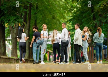 Eine große junge Gruppe von Studenten auf dem Campus, die zusammen mit Büchern und Rucksäcken zur Schule gehen Stockfoto