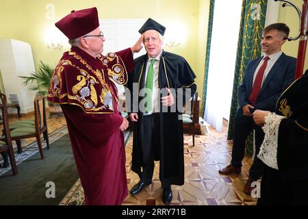 LVIV, UKRAINE - 9. SEPTEMBER 2023 - Rektor Volodymyr Melnyk (L) hilft dem ehemaligen britischen Premierminister Boris Johnson, sich für die Zeremonie zu kleiden, um die zu verleihen Stockfoto