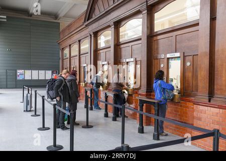 Bahnreisende stehen Schlange, um Bahntickets am Kartenbüro des Bahnhofs Manchester Victoria zu kaufen Stockfoto