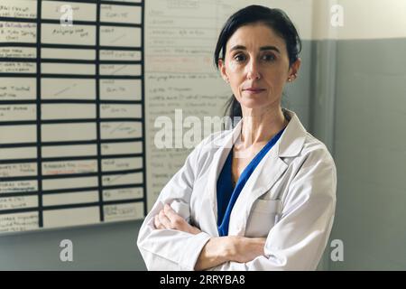 Porträt einer mittleren Ärztin trägt einen weißen Arztmantel mit einem Stethoskop um den Hals. Lächelnder Arzt, der im Krankenhaus A steht Stockfoto