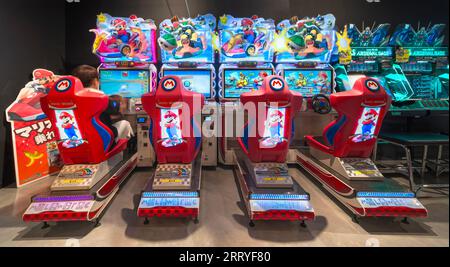 tokio, japan - 22. august 2023: Beleuchtete E-Sport-Sitze, die mit einem sitzenden Spieler im Mario Kart Arcade GP DX-Spiel von Nintendo an aufgereiht sind Stockfoto
