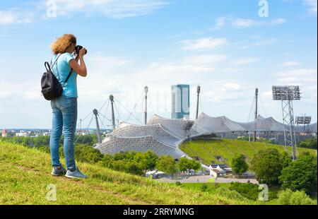 Weibliche Touristen machen Fotos vom Olympiapark im Sommer, München, Deutschland. Dieser Ort ist ein berühmtes Wahrzeichen der Stadt Munchen. Reisekonzept, Touri Stockfoto