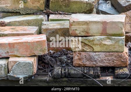 Ein Haufen rustikaler roter Ziegel ist bereit für ein kreatives Projekt im Freien Stockfoto