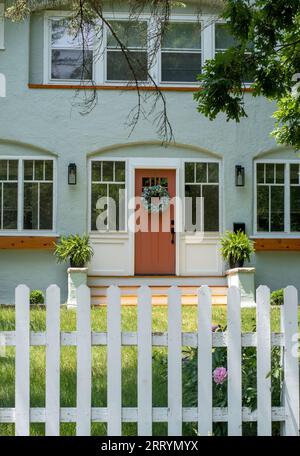Ein hübsches Haus hat einen einladenden Eingang und einen einfachen weißen Zaun Stockfoto