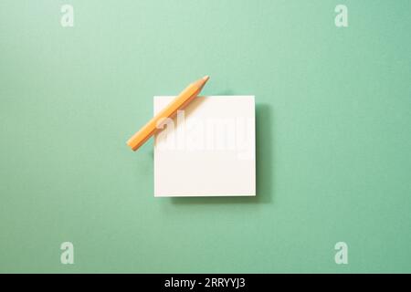 Weißes Notizpapier, Haftnotizblock mit farbigem Bleistift auf grünem Hintergrund. Draufsicht, Kopierbereich Stockfoto