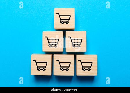 Holzwürfel mit Symbolen des Warenkorbs auf hellblauem Hintergrund, Draufsicht Stockfoto