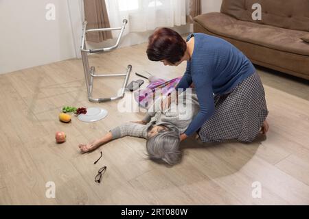 Seniorin fällt wegen Bluthochdruck im Wohnzimmer. Stockfoto