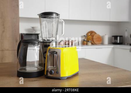 Mixer, Toaster und elektrischer Wasserkocher auf Holztisch in der Küche Stockfoto