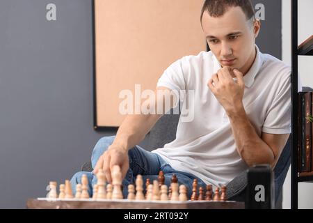 Junger Mann, der zu Hause Schach spielt Stockfoto
