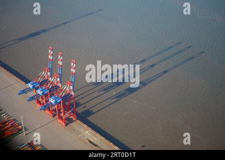 Wilhelmshaven, Deutschland. September 2023. Drei Containerbrücken im Jade-Weser-Hafen werfen ihre Schatten auf die Jade Bay. (Luftaufnahme aus einem kleinen Flugzeug). Quelle: Stefan Rampfel/dpa/Alamy Live News Stockfoto