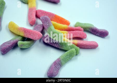 Schöne und helle bunte Süßigkeiten von Kinderbonbons in Form von süßen Regenwürmern in verschiedenen Farben auf einem weißen matten Hintergrund angeordnet. Stockfoto