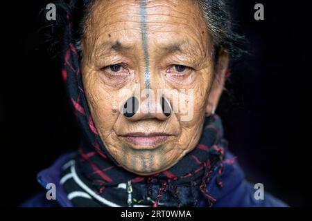Porträt einer älteren indianischen Apatani-Stammesfrau mit schwarzen hölzernen Nasenstopfen und traditionellen Gesichtstattoos, Arunachal Pradesh, Indien Stockfoto
