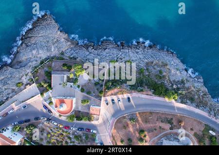 Eine Luftaufnahme über einem kleinen Leuchtturm an der felsigen Küste in Oropesa, Spanien. Stockfoto