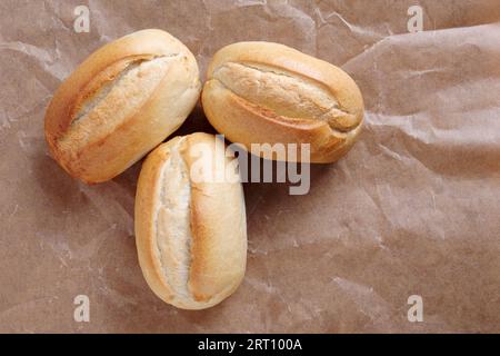 Drei Brotlaibe auf zerknittertem Papierhintergrund, Draufsicht Stockfoto