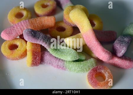 Schöne und leuchtend farbige Süßigkeiten von Kinderbonbons in Form von süßen Regenwürmern in verschiedenen Farben, amerikanischen Donuts, Lutscher. Stockfoto
