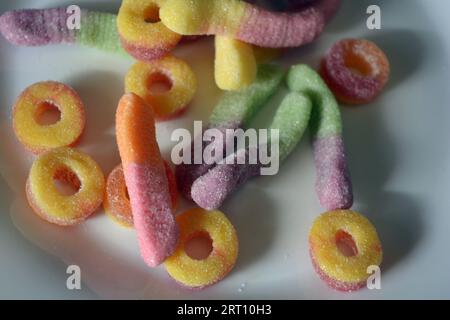 Schöne und leuchtend farbige Süßigkeiten von Kinderbonbons in Form von süßen Regenwürmern in verschiedenen Farben, amerikanischen Donuts, Lutscher. Stockfoto