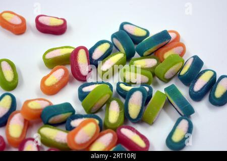 Interessante und ungewöhnliche, farbige Karamellbonbons, Süßigkeiten mit einem weißen Zentrum befinden sich auf einem weißen matten Hintergrund. Stockfoto
