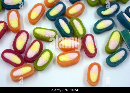 Interessante und ungewöhnliche, farbige Karamellbonbons, Süßigkeiten mit einem weißen Zentrum befinden sich auf einem weißen matten Hintergrund. Stockfoto